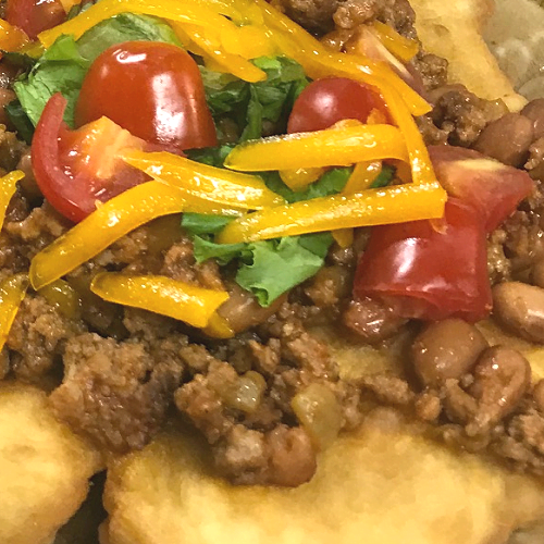 Fried Tacos with a Mexican Ground Beef Filling Topped with Tomatoes and Cheese.