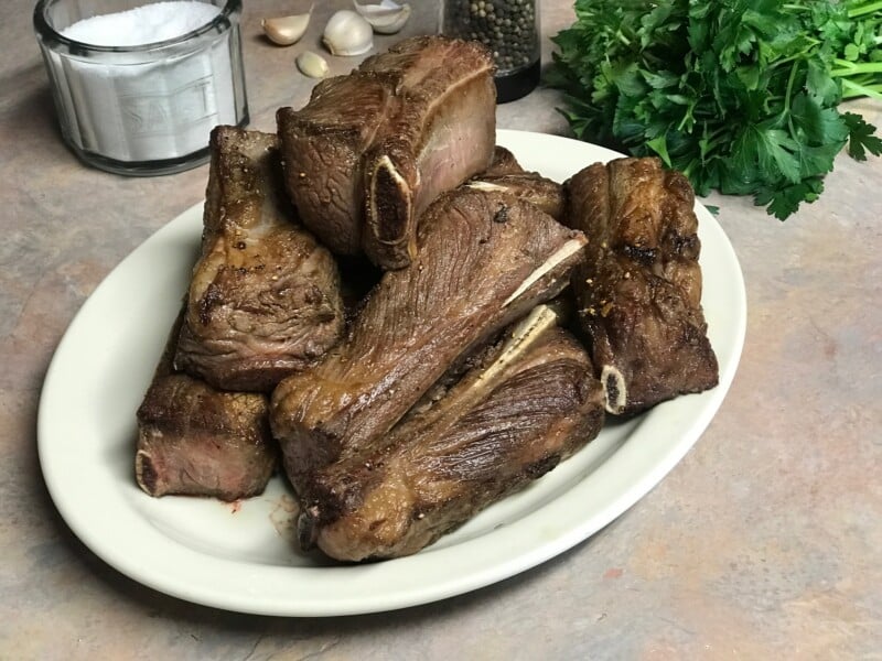browned-short-ribs Browned beef short ribs on a white plate.