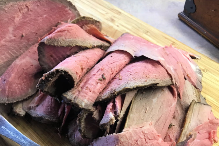 Medium rare slices of eye of round roast, in a stack.