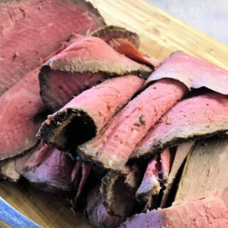 Slices of medium rare eye of round roast beef on a cutting board.