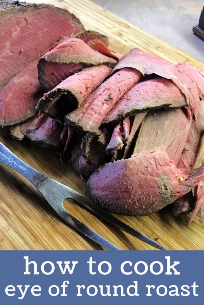 Eye of round roast that's partially sliced with a meat fork on a cutting board. 