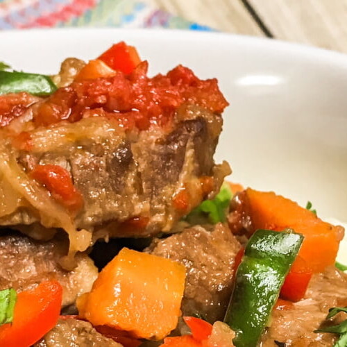 Beef Swiss Steak with veggies and gravy in a bowl.