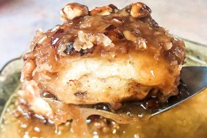 A caramel pecan sticky bun being lifted from the pan on a spatula.