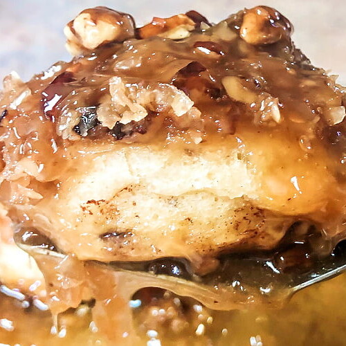 A caramel pecan sticky bun being lifted from the pan on a spatula.