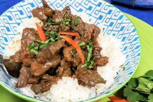 A bowl with rice topped with beef bulgogi and cilantro.