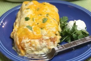 Two ground beef burritos smothered with sour cream and cheese.