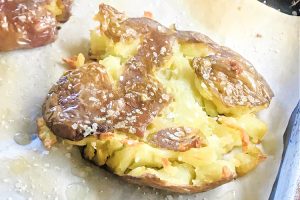 A smashed garlic potato on parchment paper.