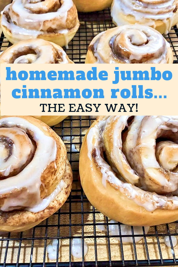 Jumbo glazed cinnamon rolls resting on a cooling rack. 