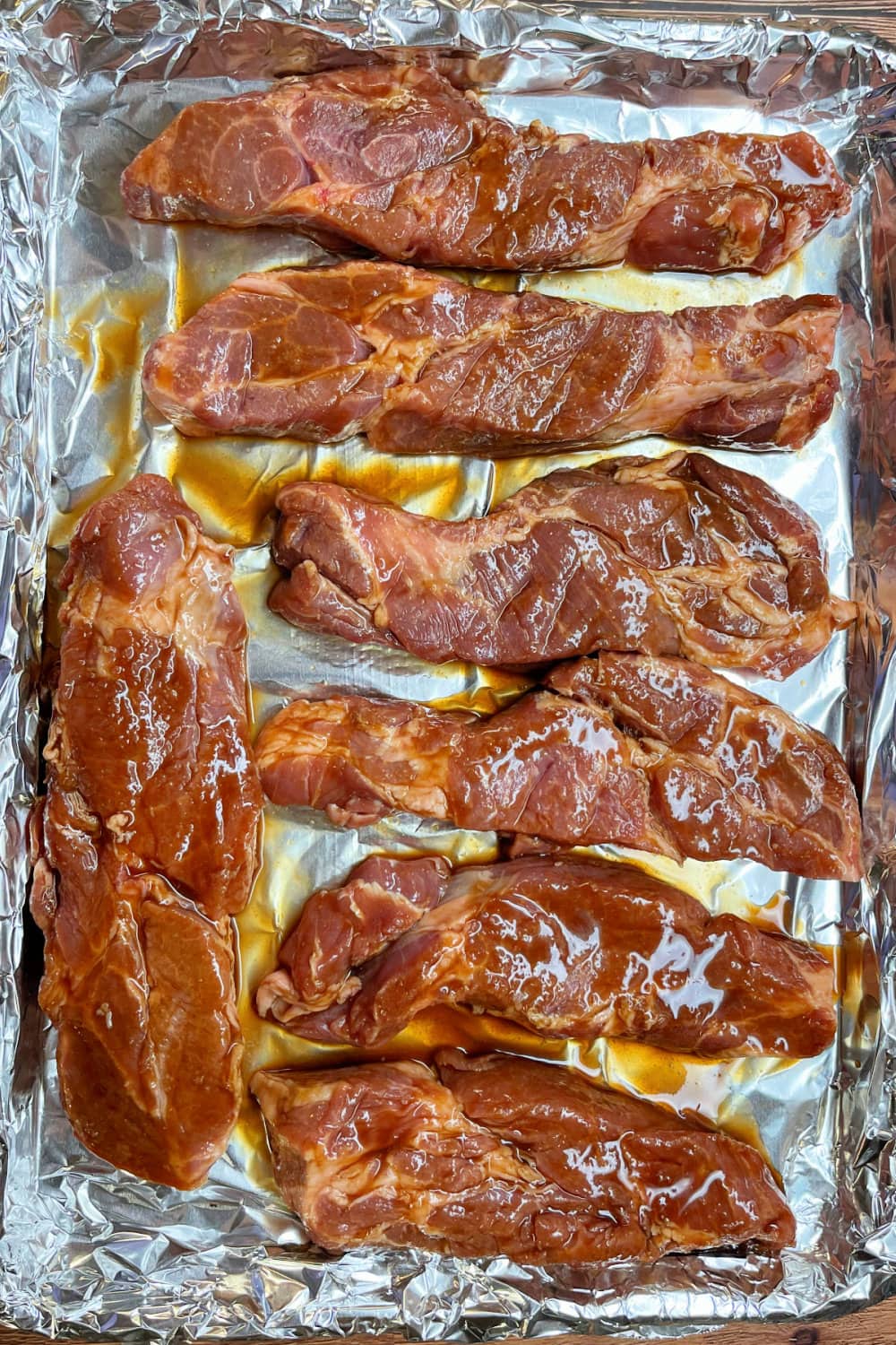 Country style pork ribs on a baking sheet lined with foil .
