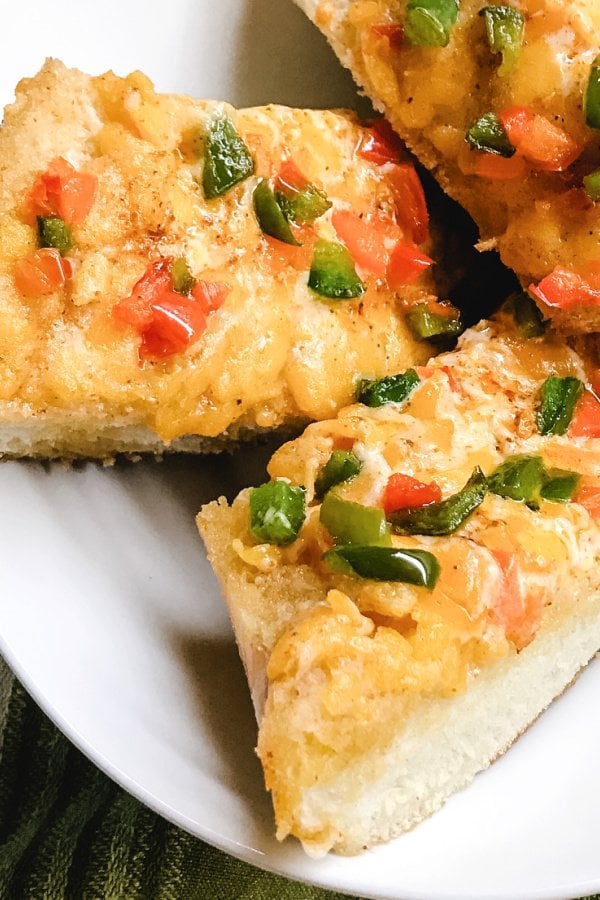 Big loaded slices of Mexican Cheese Bread piled onto a white plate. 