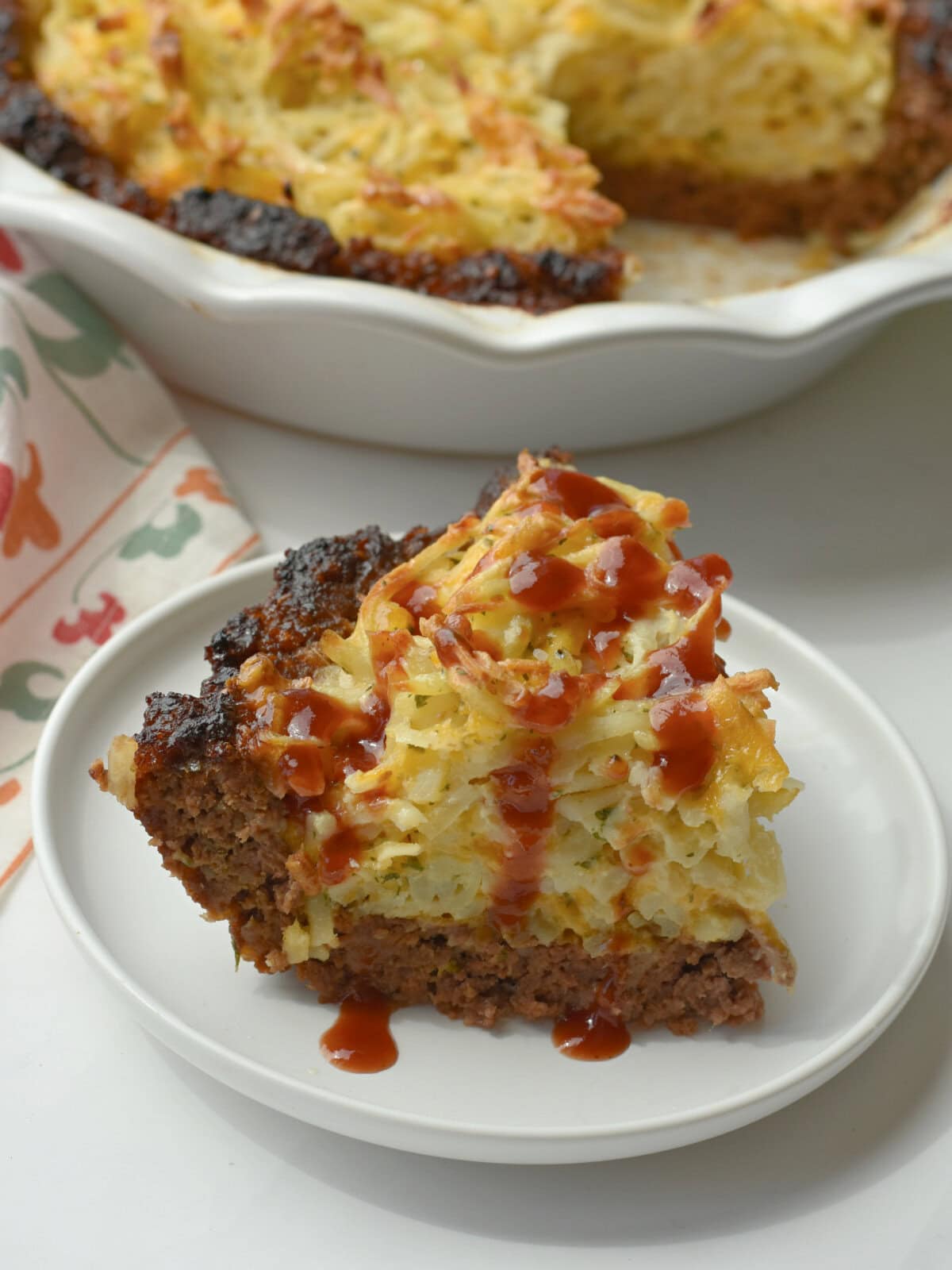 meatloaf-pie-cheesy-hashbrowns-plate Meatloaf pie with cheesy hashbrowns on a white plate.