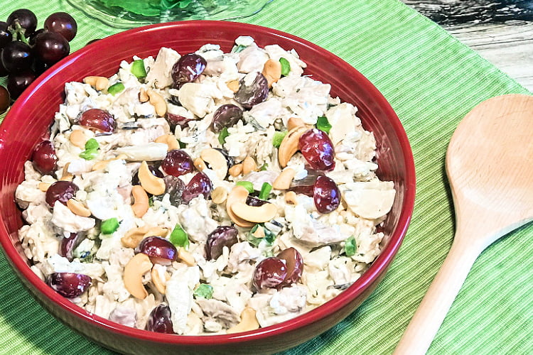 Red serving bowl loaded with chicken salad.
