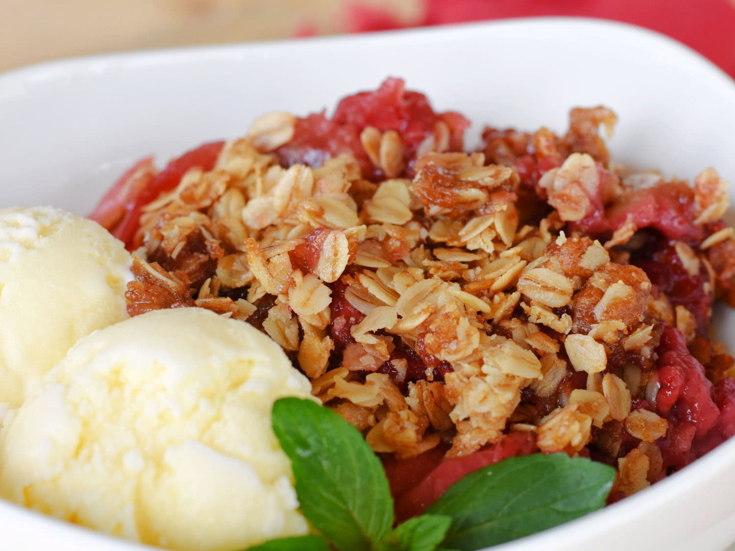 A bowl of warm Strawberry Crumble with ice cream on the side. 