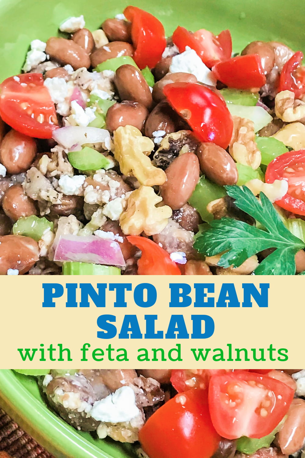 Pinto bean salad with chopped vegetables, feta crumbles, and chopped walnuts in a green bowl. 
