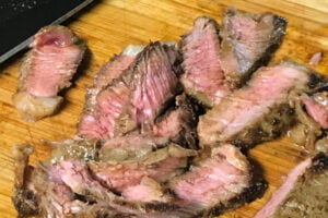 Slices of medium-rare steak on a cutting board.
