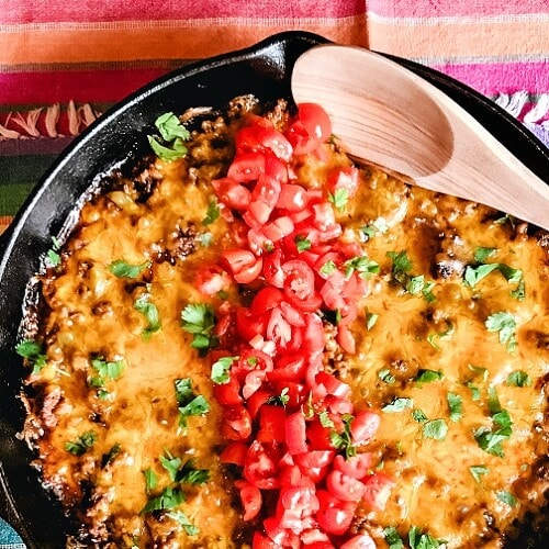 A big old pan of Tex Mex Cornbread Casserole topped with cheese and chopped tomatoes.