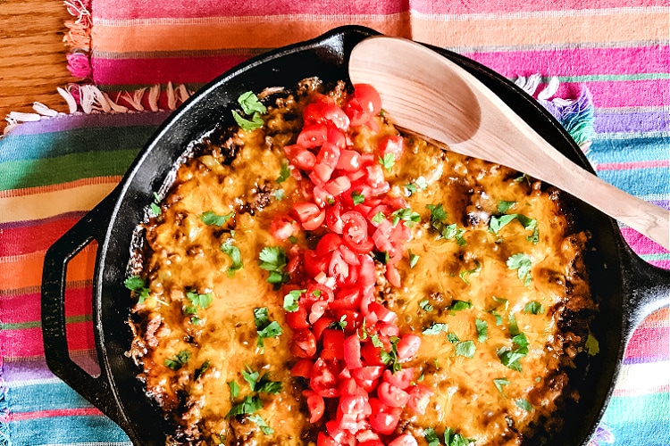 A big old pan of Tex Mex Cornbread Casserole topped with cheese and chopped tomatoes.