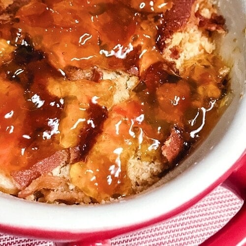 Hot and creamy pepper jelly cheese dip in a red casserole dish.