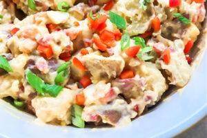A white bowl full of creamy potato salad.
