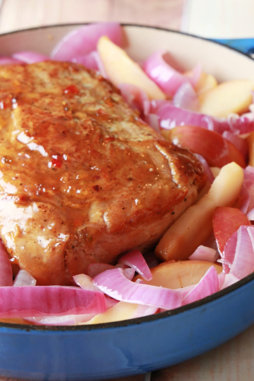 A blue cast iron skillet loaded with pepper jelly glazed pork loin. 