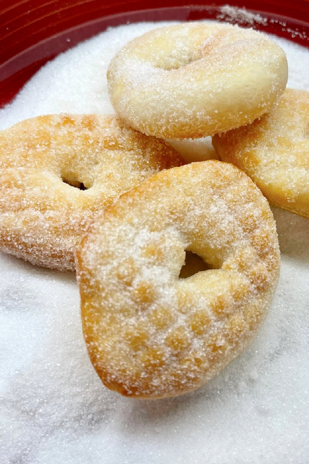 Hot doughnuts being tossed in granulated sugar. 