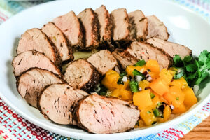 A platter full of pork tenderloin medallions with tropical salsa.