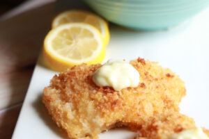 Air fryer fish fillet perched on a white platter.