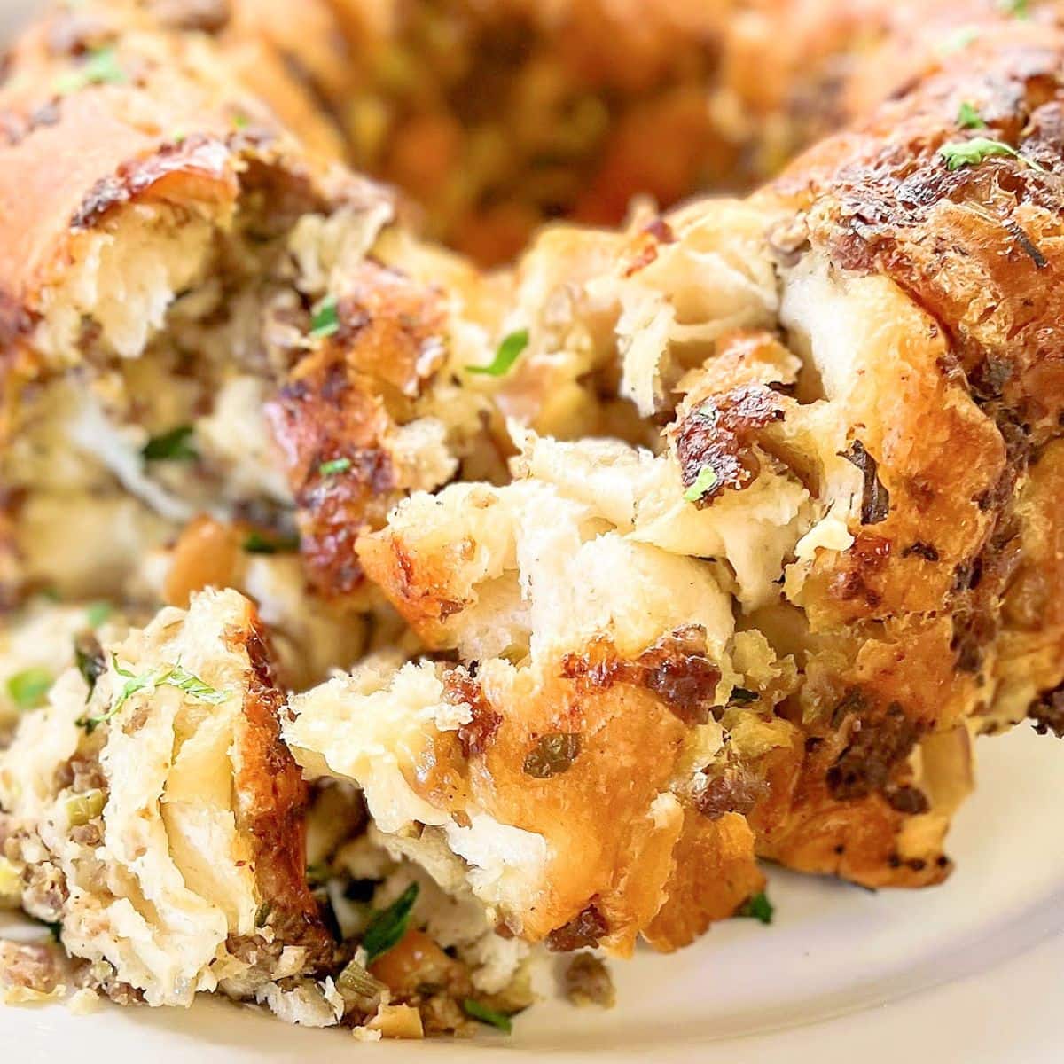 A plated holiday pull apart bread that is pulled apart showing the sausage and filling.