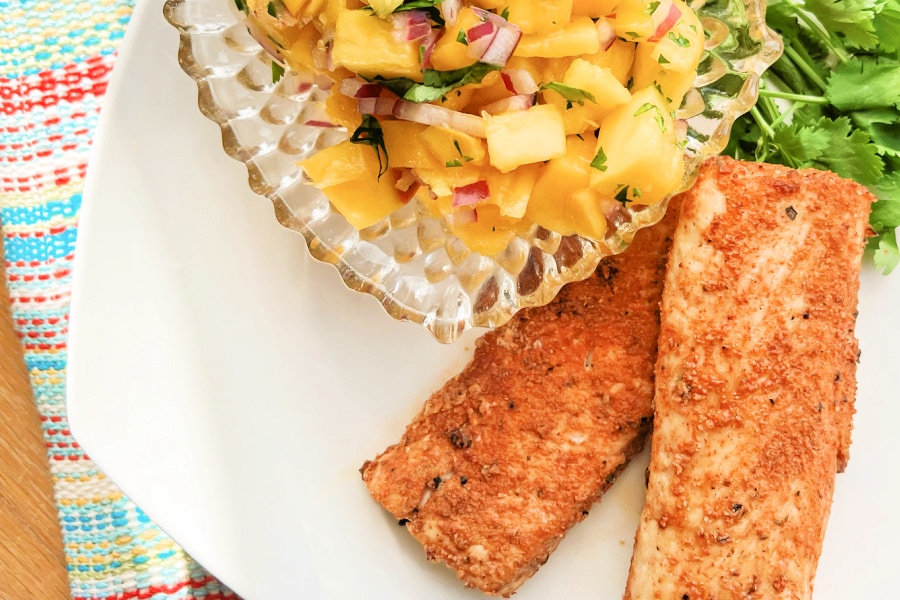 Golden brown Mahi Mahi fish fillets with a bowl of mango salsa. 