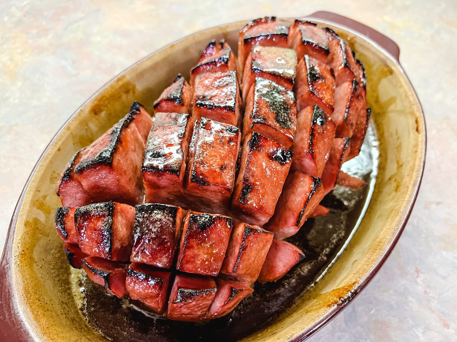 Glazed whole ham that is scored and hot from the oven. 