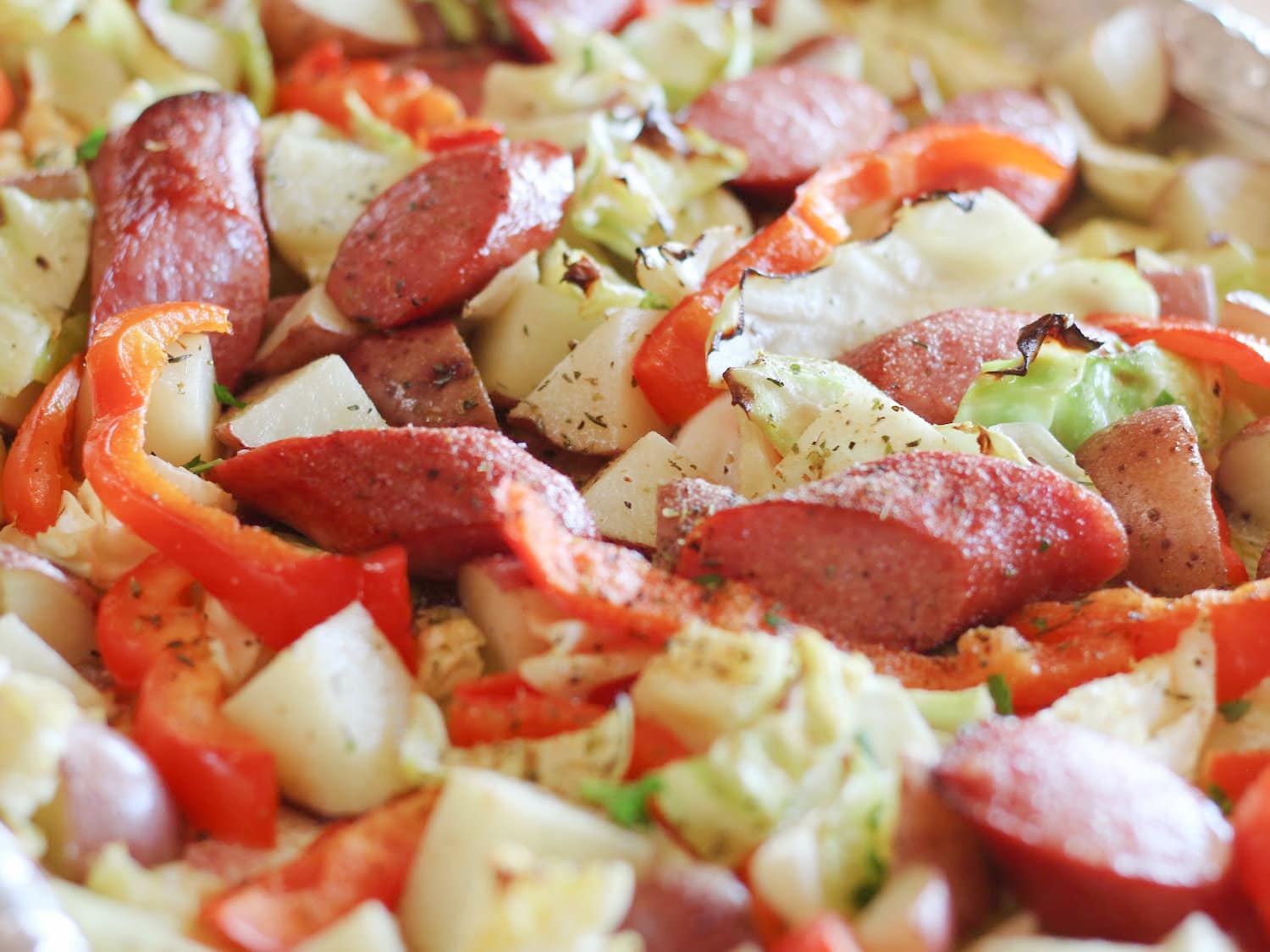 A sheet pan full of sausage, potatoes, and cabbage, fresh from the oven. 