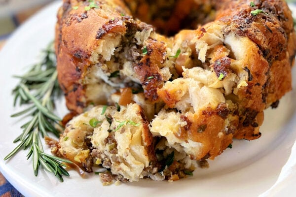 A Pull-Apart Stuffing Ring placed onto a white platter with rosemary as a garnish.