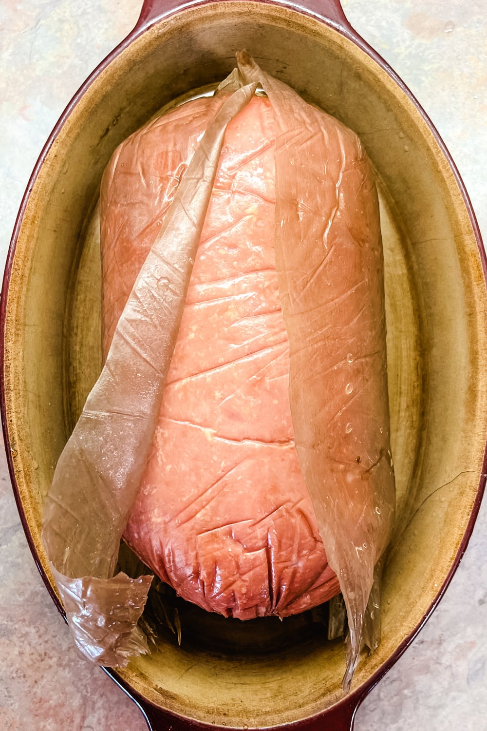 Cooked boneless ham with cut package to go into the oven. 