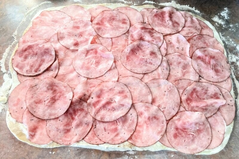 Ham overlapped onto a rectangle of bread dough.