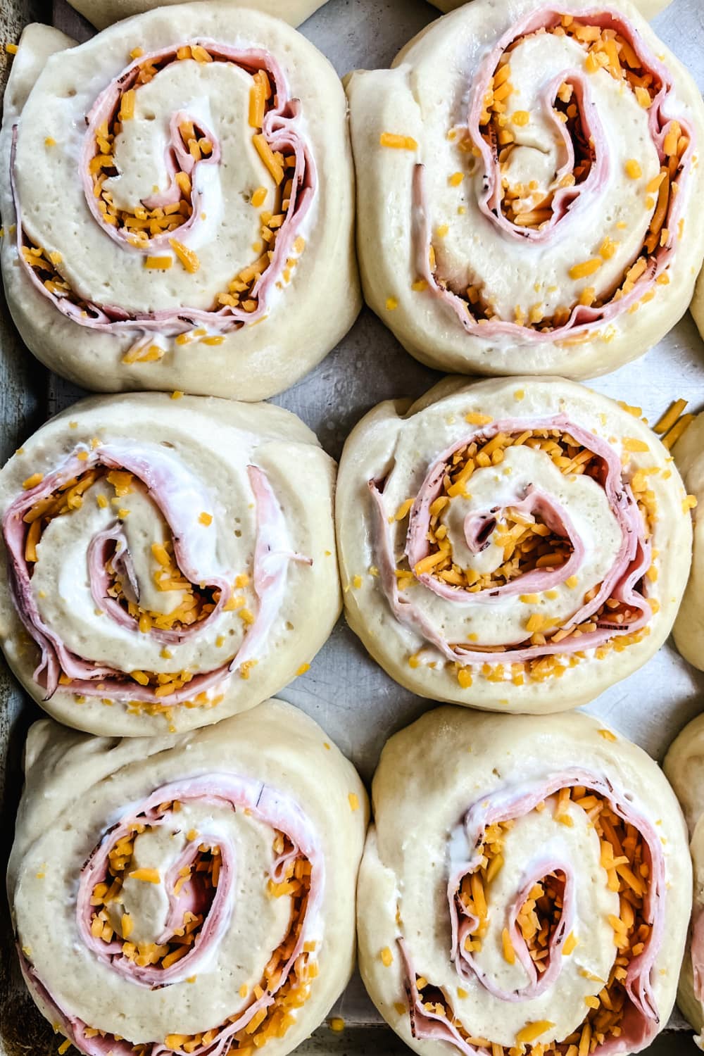 Ham and cheese rolls on a baking sheet ready for the oven.