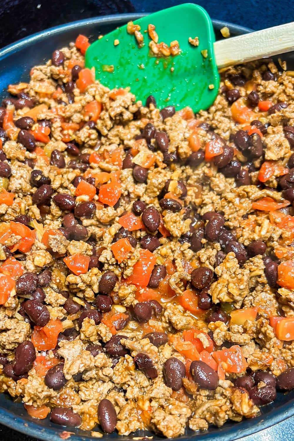 A skillet of filling made from ground beef, diced tomatoes, and black beans. 