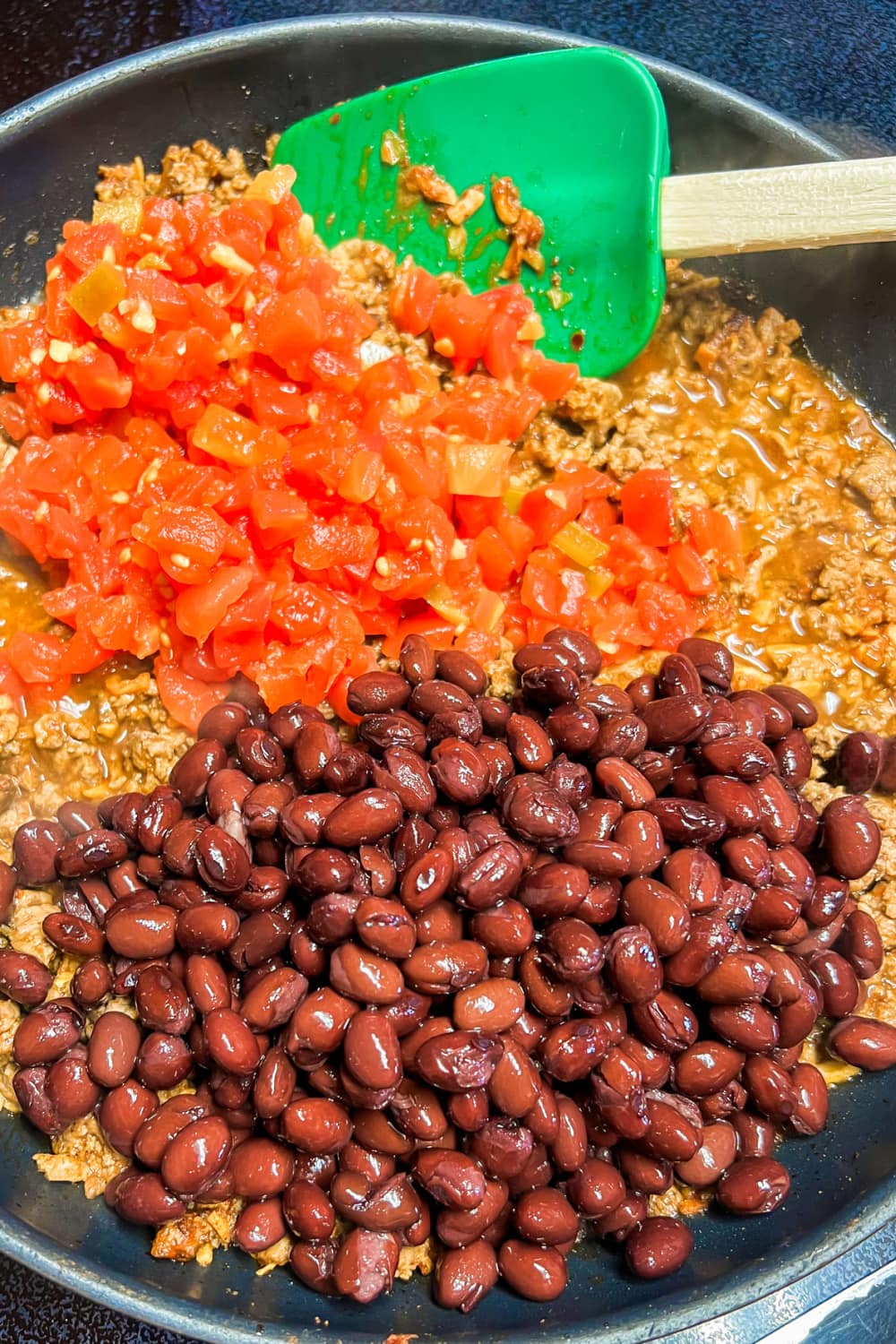 Ground beef skillet with black beans and tomatoes ready to stir in. 