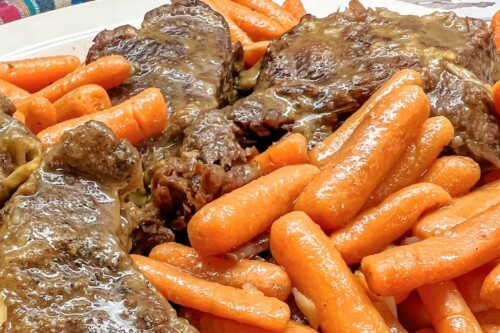 Tender roast beef with baby carrots on the side.