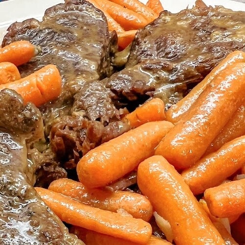 Tender roast beef with baby carrots on the side.