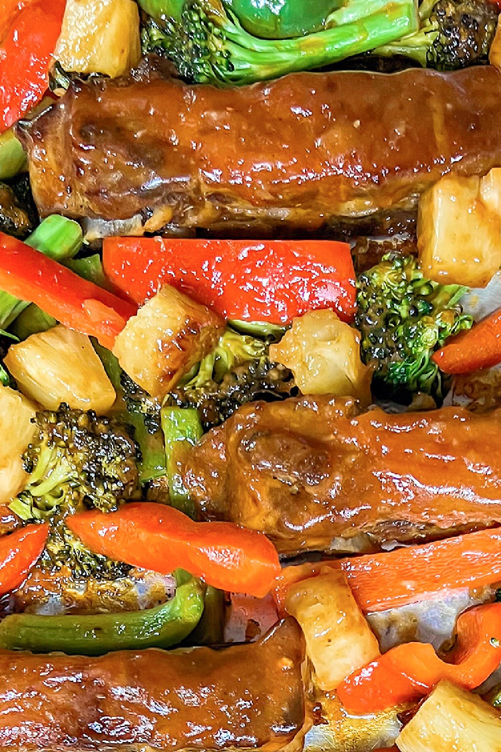 A beautiful assortment of roasted vegetables with pork ribs on a sheet pan. 