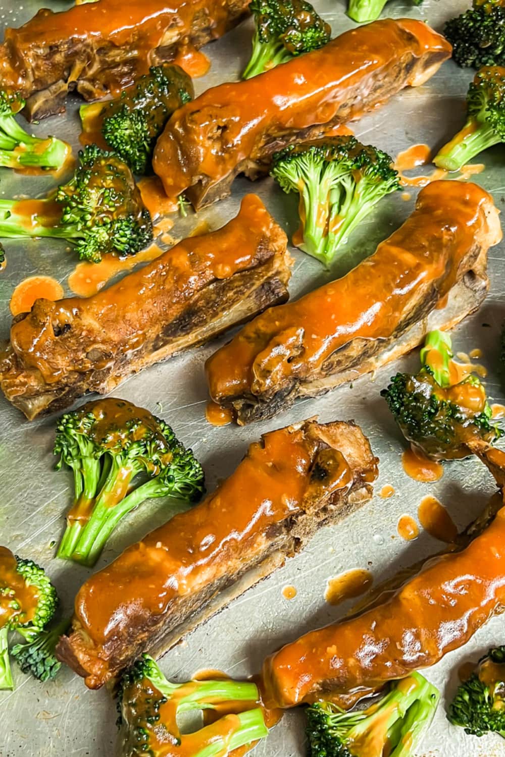 Baked ribs slathered with more sweet and sour sauce, surrounded with raw broccoli. 