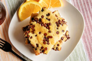 Stacked chocolate chip pancakes on a white plate.