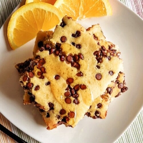 Stacked chocolate chip pancakes on a white plate.