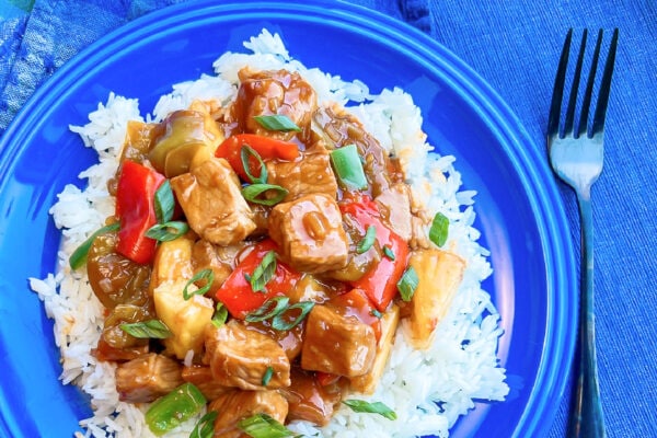 A large helping of sweet and sour pork on a bed of warm rice. 
