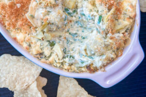 Warm and creamy spinach artichoke dip in a white casserole dish.