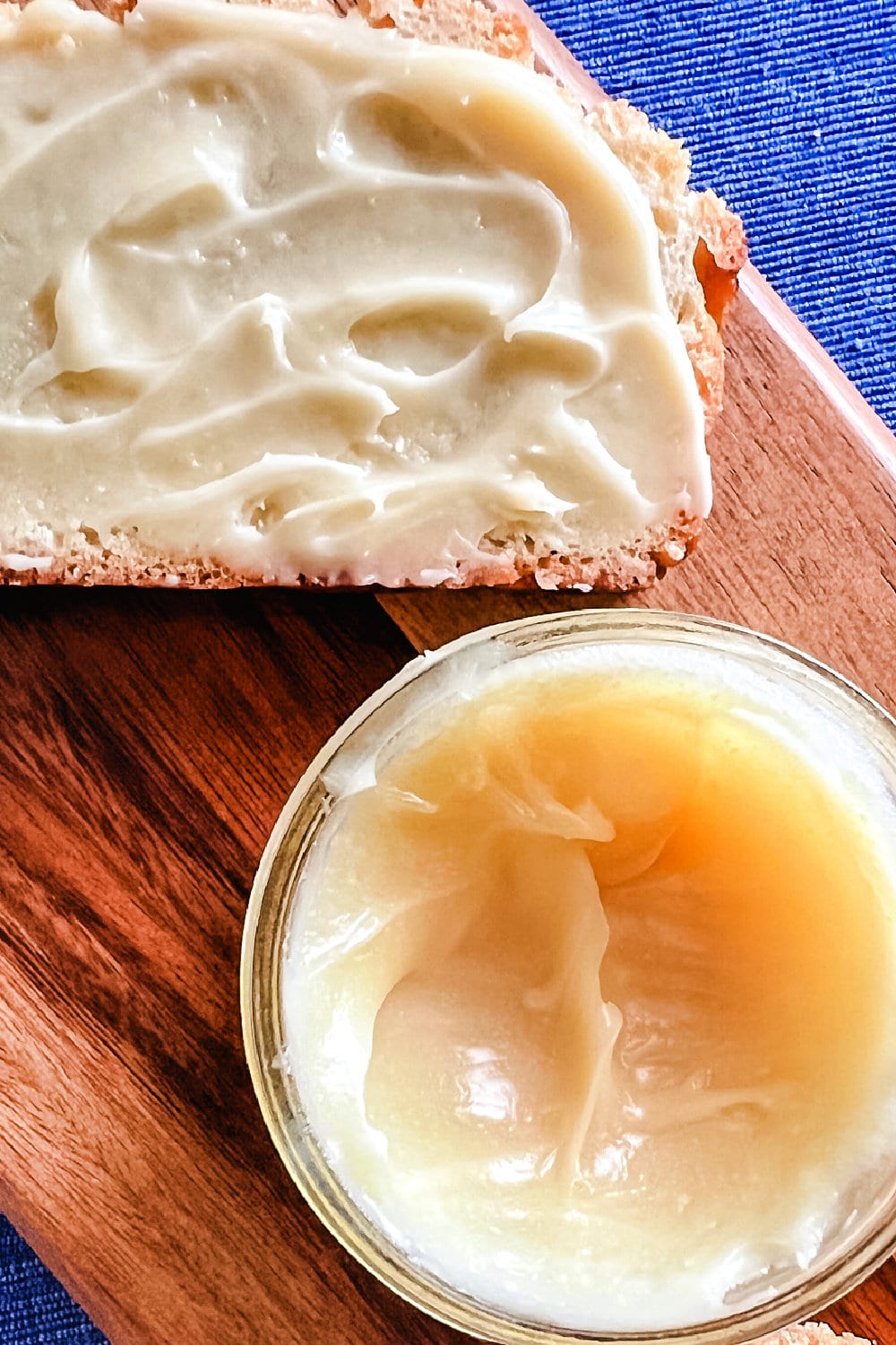 An open jar of creamy honey butter spread beside a slide of bread. 