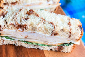 Turkey tea finger sandwiches on a wooden cutting board.