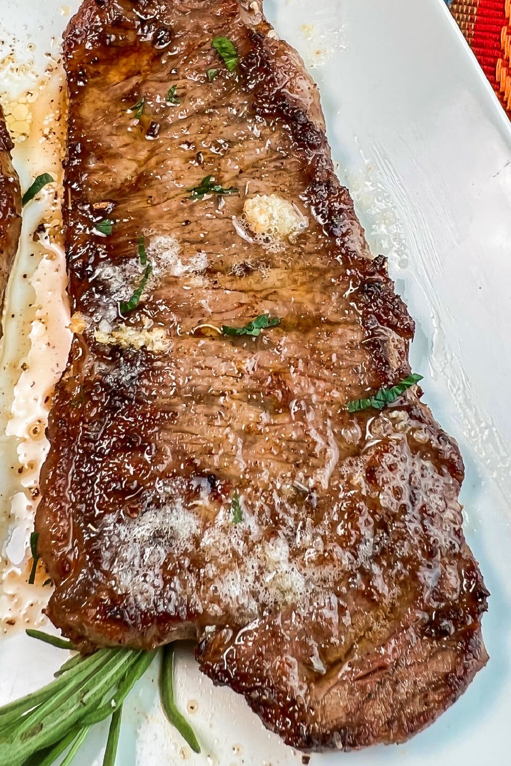 Garlic butter sauce spooned over a steak with parsley garnish. 