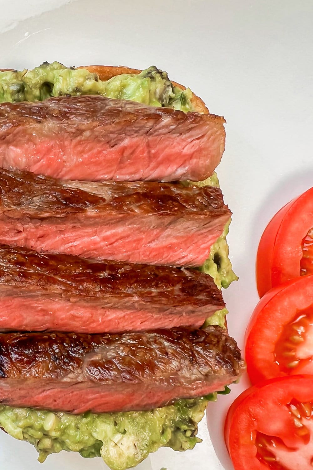 Grilled Rib Eye Steak Slices nestled into a bed of mashed avocado. 
