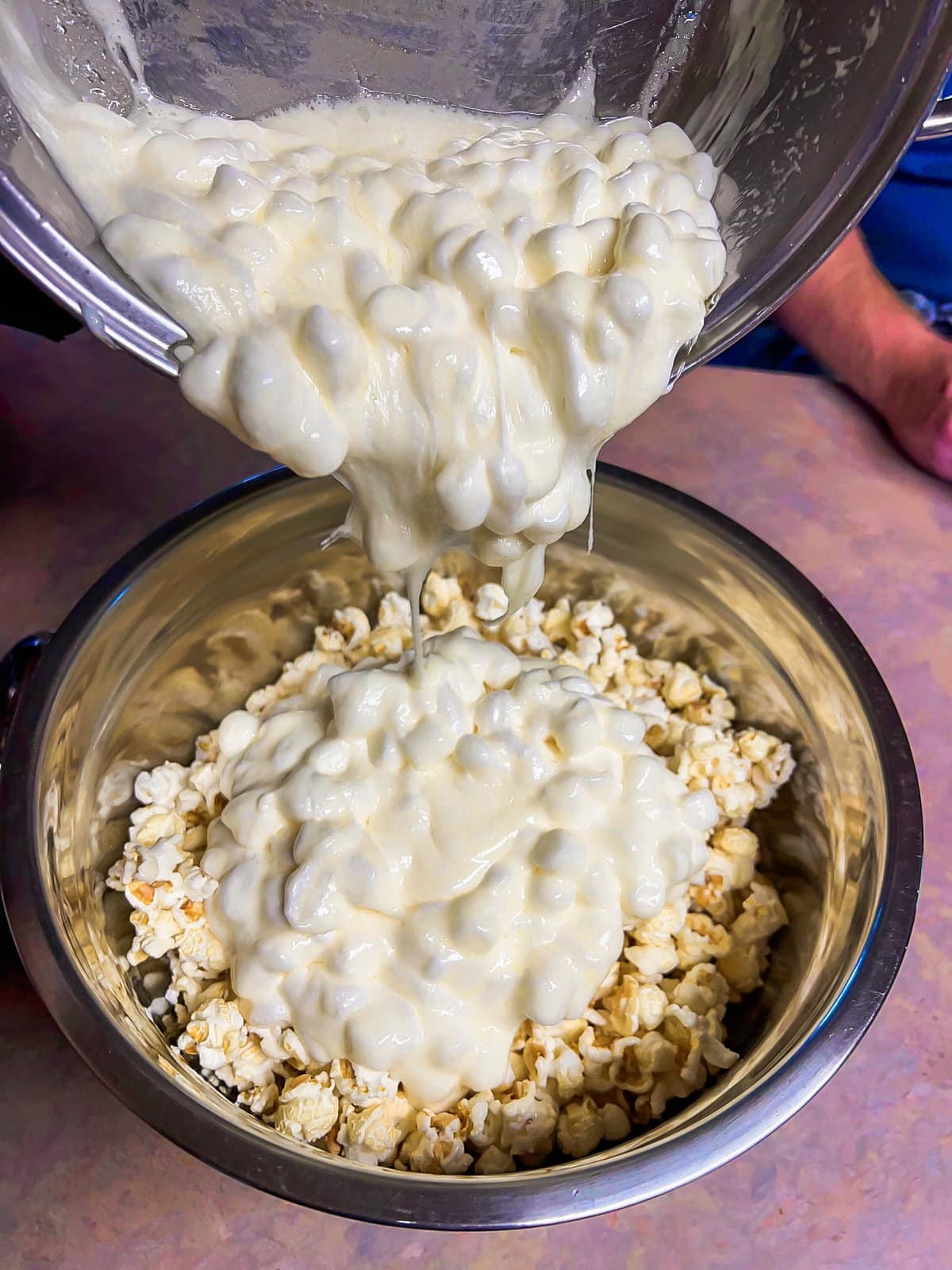 Marshmallow mixture poured over kettle corn in a bowl.